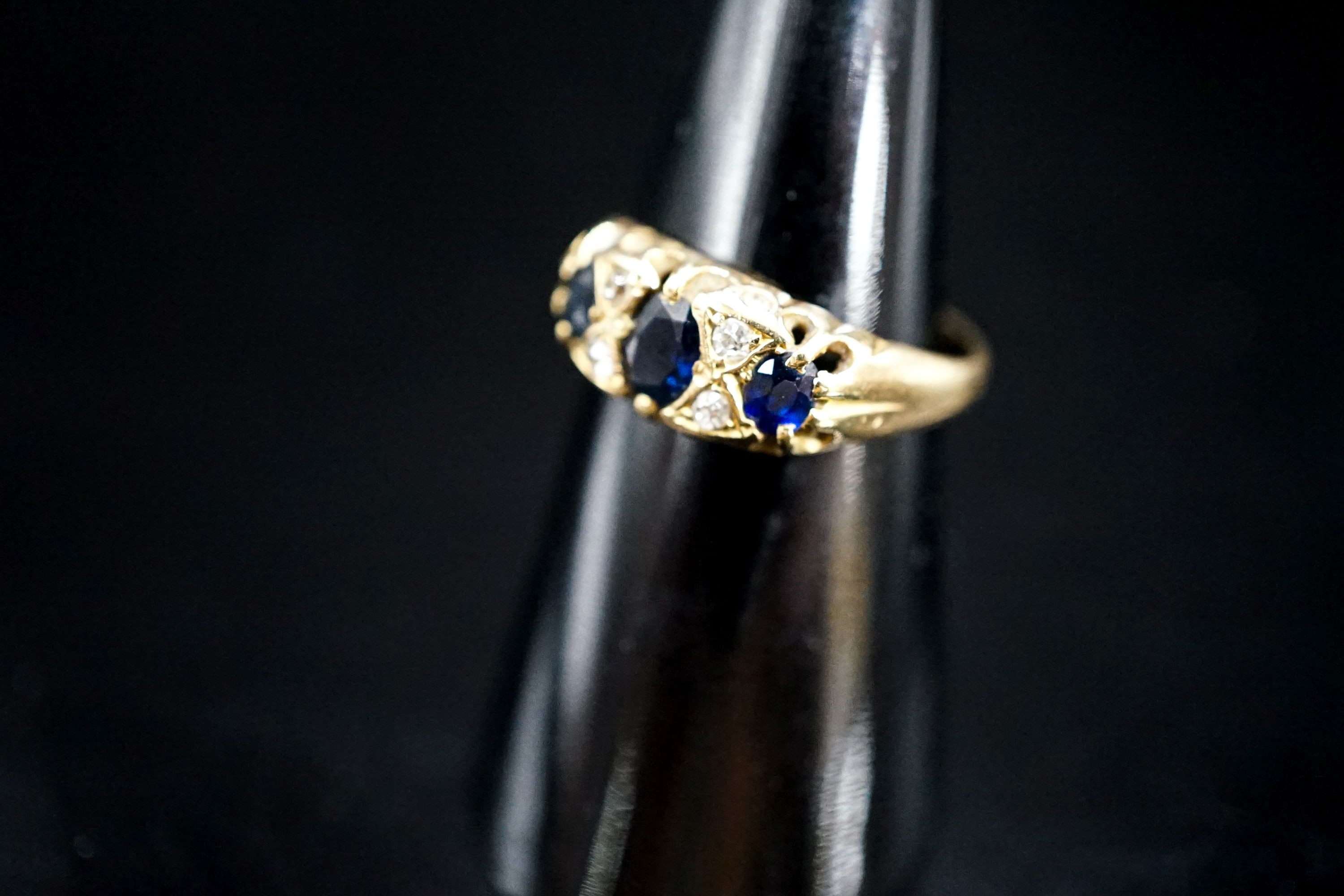 A late Victorian 18ct gold, three stone sapphire and four stone diamond chip set ring, size L, gross weight three grams.